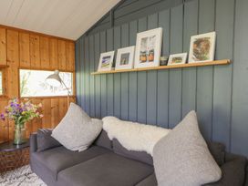 A living room with a sofa and pictures on a shelf at Blue Pine Lodge in Dornoch