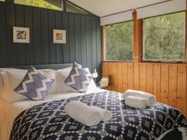 A bedroom with a bed and windows overlooking nature at Blue Pine Lodge in Dornoch