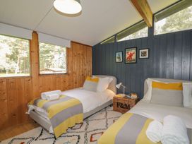 A bedroom with two beds and windows at Blue Pine Lodge in Dornoch