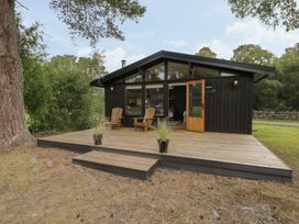 A wooden cabin with a deck and chairs at Blue Pine Lodge in Dornoch