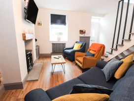 A living room with a sofa, armchairs, coffee table and television at 8 Watkin Street in Conwy