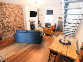 A living room with a sofa, armchair, coffee table, and television at 8 Watkin Street Conwy
