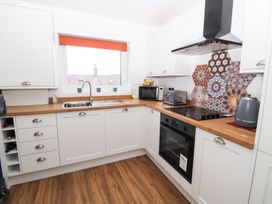 A kitchen with a sink, microwave, and stove at 8 Watkin Street, Conwy