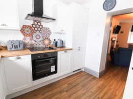 A kitchen with a countertop, oven, toaster, kettle, and tiles at 8 Watkin Street Conwy