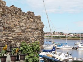 A view of a stone wall and boats on water at 8 Watkin Street Conwy