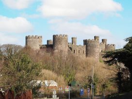 A castle with towers and trees under a cloudy sky near a road at 8 Watkin Street Conwy