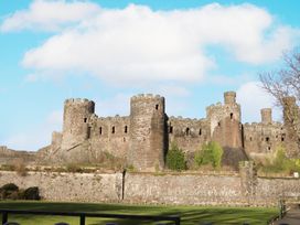 A castle with towers and walls on a grass field at 8 Watkin Street, Conwy