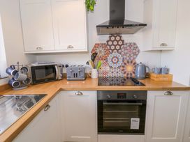 A kitchen with microwave, toaster, kettle, and patterned backsplash at 8 Watkin Street Conwy