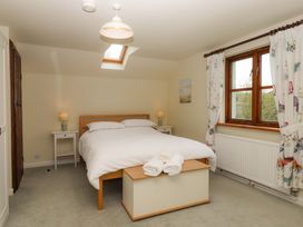 A bedroom with a bed, nightstand, and window at The Milking Shippon at Thorne near Great Torrington
