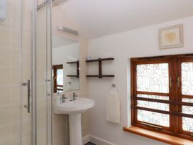 A bathroom with shower, sink, and window at The Milking Shippon at Thorne in Langtree near Great Torrington