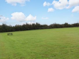 An open grassy area with a picnic table and hedge at The Milking Shippon at Thorne Langtree near Great Torrington