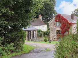 A house and cabin surrounded by greenery at The Milking Shippon at Thorne near Great Torrington