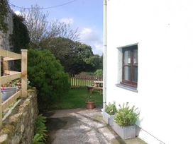 A garden with a stone wall and table at The Milking Shippon at Thorne near Great Torrington