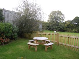 A garden with a wooden table and benches at The Milking Shippon at Thorne in Langtree near Great Torrington