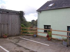 An outdoor parking area with a wooden shed and flower pots at The Milking Shippon at Thorne Langtree near Great Torrington