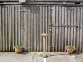 An outdoor area with a wooden door and parking sign at The Milking Shippon at Thorne Langtree near Great Torrington