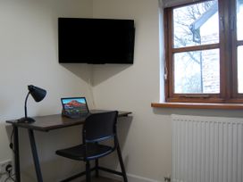 An office with a desk, laptop, and television at The Milking Shippon at Thorne Langtree near Great Torrington