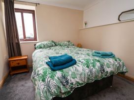 A bedroom with a double bed and a nightstand at Ty Cerrig apartment