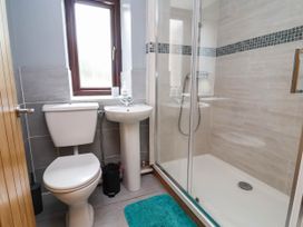 A bathroom with a toilet, sink, and shower at Ty Cerrig apartment 