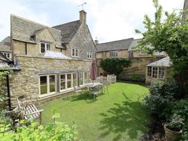 A garden with a stone house and seating area at The Coach House in Burford