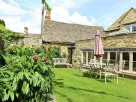 A garden with a bench and table at The Coach House in Burford