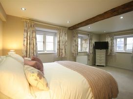 A bedroom with a bed and a TV at The Coach House in Burford