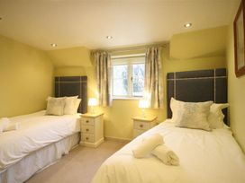 A bedroom with two beds and a window at The Coach House in Burford
