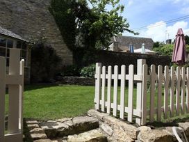 A garden with a fence and stone wall at The Coach House in Burford