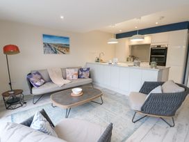 A living room with a sofa and kitchen counter at 2 Lon Y Dryw in Trearddur Bay