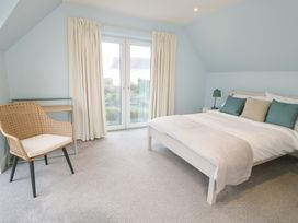 A bedroom with a bed and a chair at 2 Lon Y Dryw in Trearddur Bay