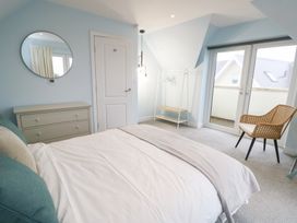 A bedroom with a bed, dressing table, mirror, and chair at 2 Lon Y Dryw in Trearddur Bay