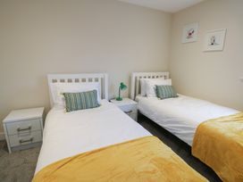 A bedroom with two beds and a nightstand at 2 Lon Y Dryw in Trearddur Bay