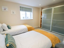 A bedroom with two beds and a wardrobe at 2 Lon Y Dryw in Trearddur Bay