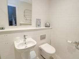 A bathroom with a sink, toilet, and mirror at 2 Lon Y Dryw in Trearddur Bay