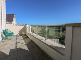 A balcony with green chairs overlooking a field at 2 Lon Y Dryw in Trearddur Bay