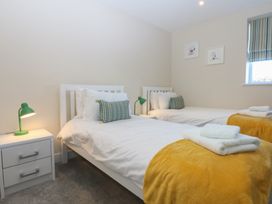 A bedroom with two beds and a lamp at 2 Lon Y Dryw in Trearddur Bay