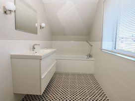 A bathroom with a bathtub, sink, and window at 2 Lon Y Dryw Trearddur Bay
