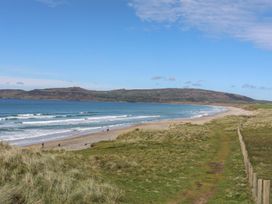 A beach scene with waves and a path leading to the shore at Cilan - 2 Ty'n Don Llanengan near Abersoch