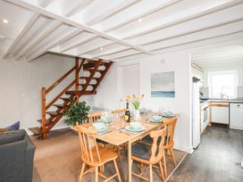 A dining room with a table set for a meal and a staircase at Rhiw - 1 Ty'n Don Abersoch