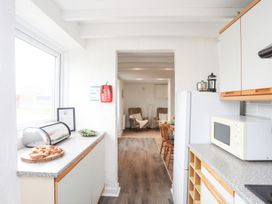 A kitchen with a window, refrigerator, and microwave at Rhiw - 1 Ty'n Don Abersoch