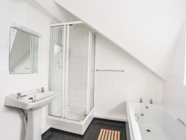 A bathroom with a sink, shower, mirror, bathtub, and towel rack at Rhiw - 1 Ty'n Don Abersoch