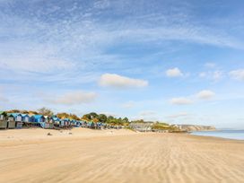 A beach with colorful beach huts and a clear sky at Rhiw - 1 Ty'n Don Abersoch