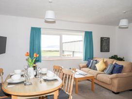 A living room with a table and chairs, and a couch at Oer - 8 Ty'n Don Llanengan near Abersoch