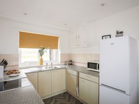 A kitchen with a refrigerator, sink, and microwave at Oer - 8 Ty'n Don, Llanengan near Abersoch