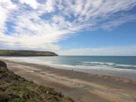 A beach with ocean waves and people walking at Ysgo - 6 Ty'n Don Abersoch