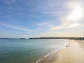 A beach scene with people walking and islands in the distance at Ysgo - 6 Ty'n Don in Abersoch