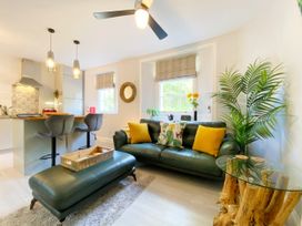 A living room with a sofa and kitchen area at Meadfoot Bay Apartment at Hesketh Crescent Torquay