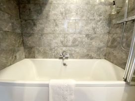 A bathtub with a showerhead and towel in a bathroom at Meadfoot Bay Apartment at Hesketh Crescent, Torquay