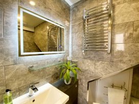 A bathroom with a mirror, sink, and towel radiator at Meadfoot Bay Apartment at Hesketh Crescent in Torquay