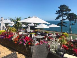 An outdoor seating area with umbrellas and flowers at Meadfoot Bay Apartment at Hesketh Crescent in Torquay